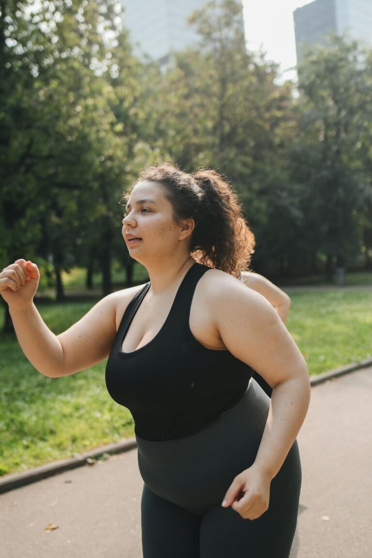 Confident plus-size woman running in a sunny park promoting active lifestyle and fitness.